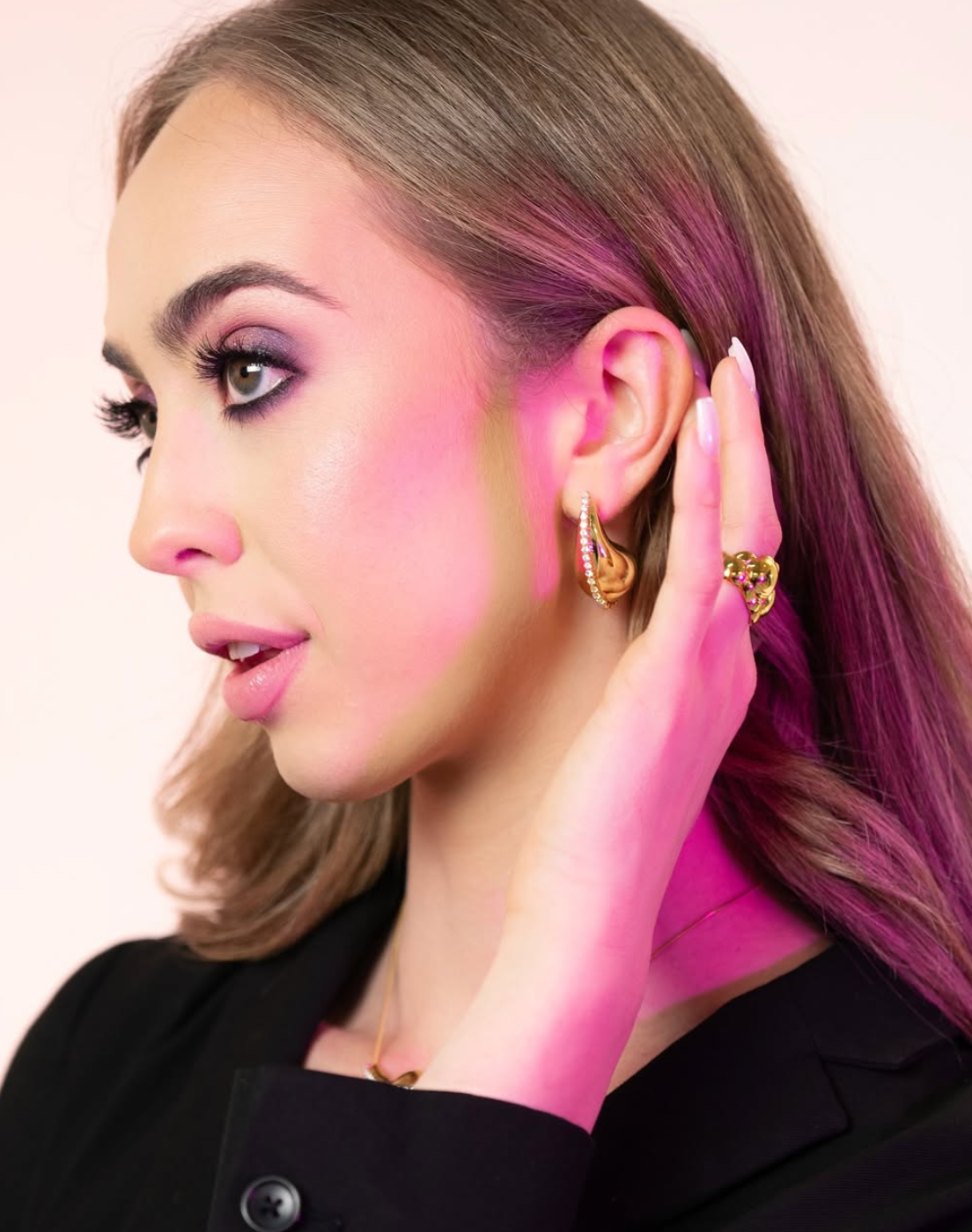 Profile beauty shot of Kristin wearing gold Leconi earrings and a ring