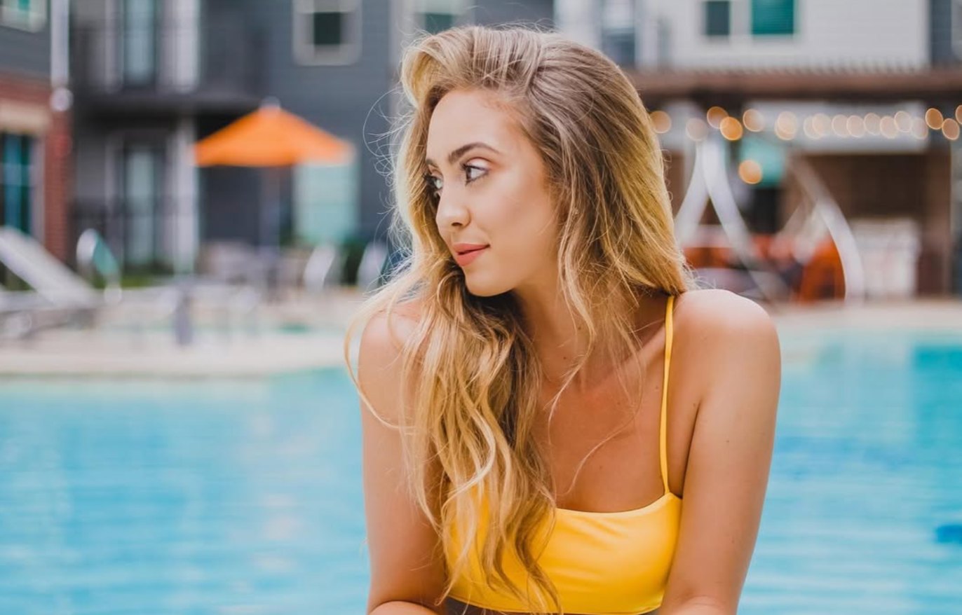 Kristin in a yellow top by a pool, looking over her shoulder